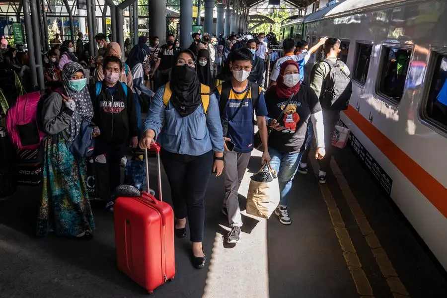 Passengers prepare to board a train at Gubeng station in Surabaya on April 19, 2023, as people head to their hometowns ahead of the Eid al-Fitr holiday which marks the end of the holy month of Ramadan. (Photo by JUNI KRISWANTO / AFP)