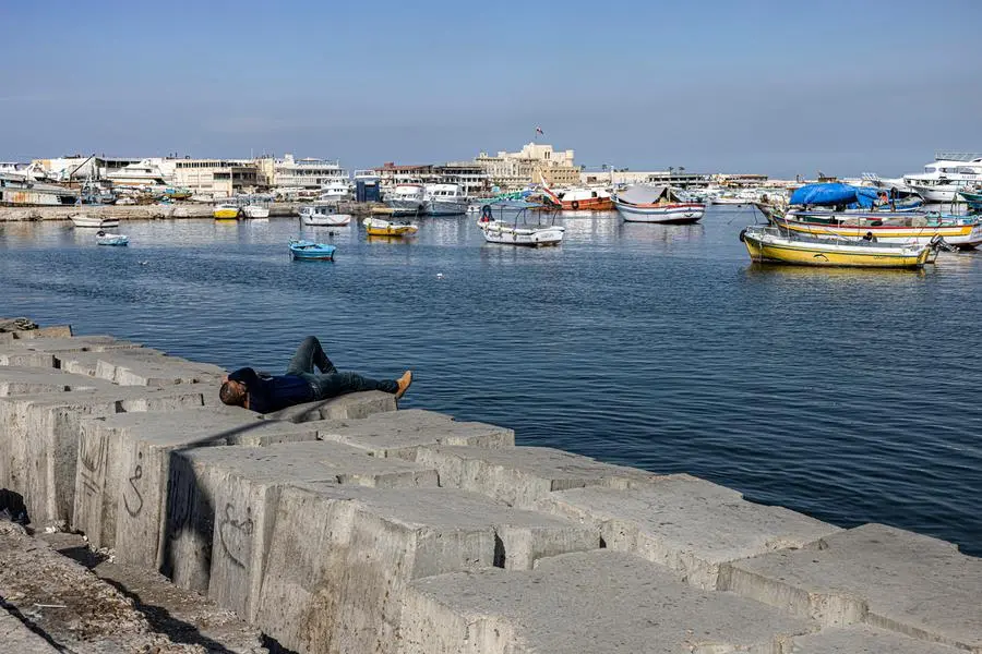 A man lies on one of the concrete blocks installed to break the Mediterranean sea waves along the corniche in Egypt's northern Mediterranean coastal city of Alexandria on October 31, 2022. - With global warming, rising sea levels and sinking land, Egypt could lose one of its treasures: the second city of Alexandria, along with its historic and ancient ruins. Its millions of inhabitants will have no choice but climate exile. Already, hundreds of Alexandrians have had to leave apartments weakened by flooding, once in 2015 and again in 2020. They are the first of a long line, warns Egypt's ministry of water resources and irrigation. (Photo by Khaled DESOUKI / AFP)