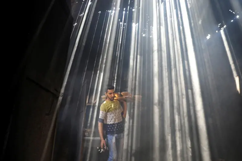 A Palestinian worker carries clay pots as the sun rays penetrate through the ceiling of a pottery workshop in Gaza City June 11, 2019. REUTERS/Mohammed Salem. Image used for illustrative purpose. , Reuters Images