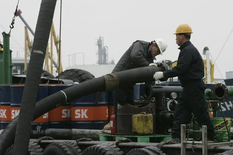 Workers on a ship load oil at a port of SK Energy\\'s main factory in Ulsan, about 410 km (256 miles) southeast of Seoul, February 25, 2009. South Korea will provide Iraq with $3.55 billion worth of infrastructure in return for oil field stakes, the Energy Ministry said on Tuesday. REUTERS/Jo Yong-Hak , Reuters Images/Jo Yong-Hak 