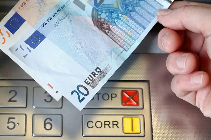 FILE PHOTO: A woman holds a 20 and 50 Euro bank notes in front of an ATM in this illustration picture taken in Bern January 16, 2015. REUTERS/Thomas Hodel. , Reuters