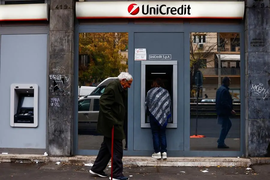 A person uses an ATM as people walk past the UniCredit bank branch in Rome, Italy, November 25, 2024. REUTERS/Yara Nardi. Image used for illustrative purpose. , Reuters