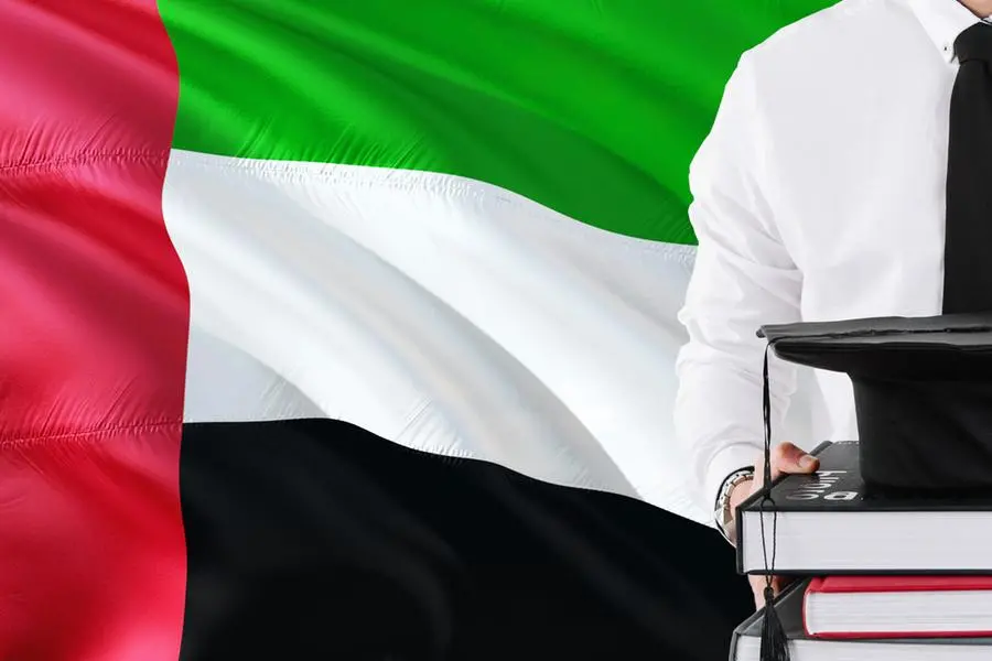 Successful student education concept. Holding books and graduation cap over United Arab Emirates flag background. Image used for illustrative purpose. Image courtesy: Getty Images/ Sezer Ozger