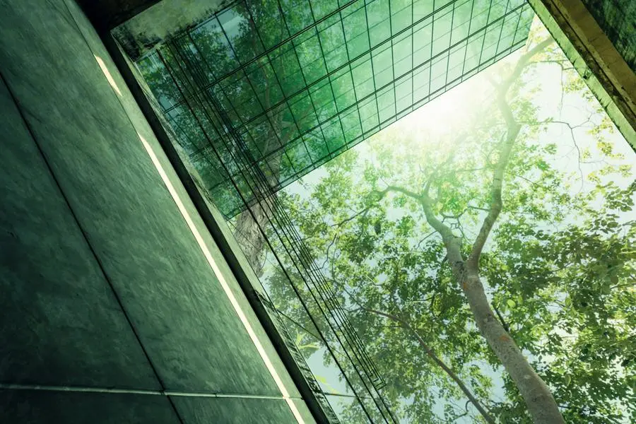 Sustainble green building. Eco-friendly building in modern city. Sustainable glass office building with tree for reducing carbon dioxide. Office with green environment. Corporate building reduce CO2. Image used for illustrative purpose. Image courtesy: Getty Images/ Fahroni , Getty Images