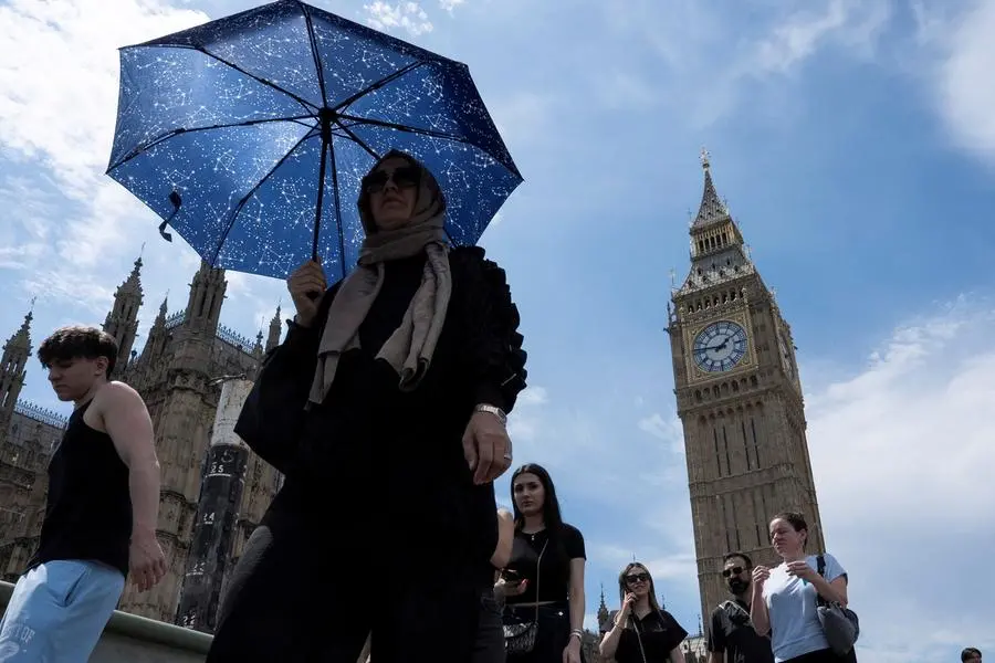 FILE PHOTO: A woman uses an umbrella for shade near Big Ben, during warm weather as temperatures rise across the UK, in London, Britain, July 1, 2025. REUTERS/Carlos Jasso. , Reuters