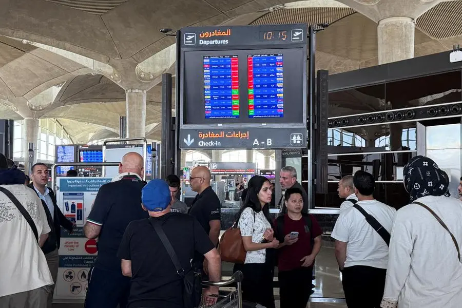 People stand in front of a flight information display screen showing information about delayed and cancelled flights, at Queen Alia International Airport in Amman, Jordan June 13, 2025. REUTERS/STRINGER , Reuters/REUTERS