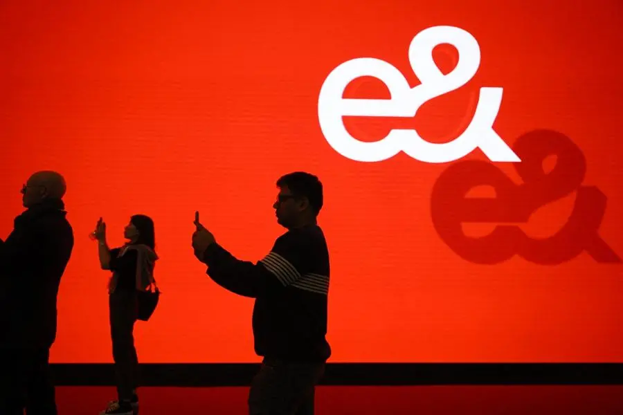 Visitors use their phone next to UAE state-owned telecommunications company Etisalat by e& corporation\\'s logo during the Mobile World Congress (MWC), the telecom industry\\'s biggest annual gathering, in Barcelona on February 26, 2024. The world\\'s biggest mobile phone fair throws open its doors in Barcelona with the sector looking to artificial intelligence to try and reverse declining sales. (Photo by Josep LAGO / AFP) , AFP