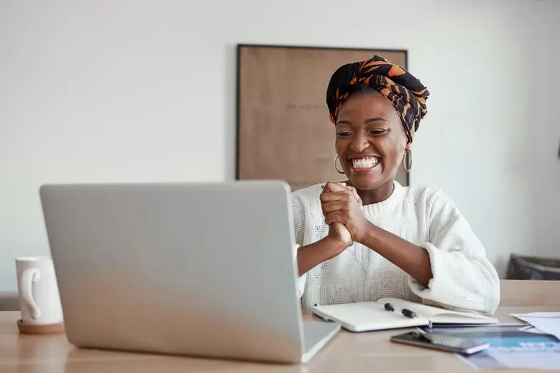 Shot of a young woman cheering while working on a laptop at home. Image used for illustrative purpose. Getty Images , Getty Images
