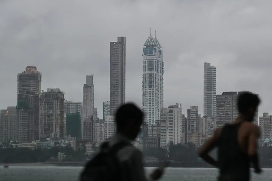 Men walk near the seafront overlooking the city skyline in Mumbai on September 26, 2024. (Photo by Punit PARANJPE / AFP).