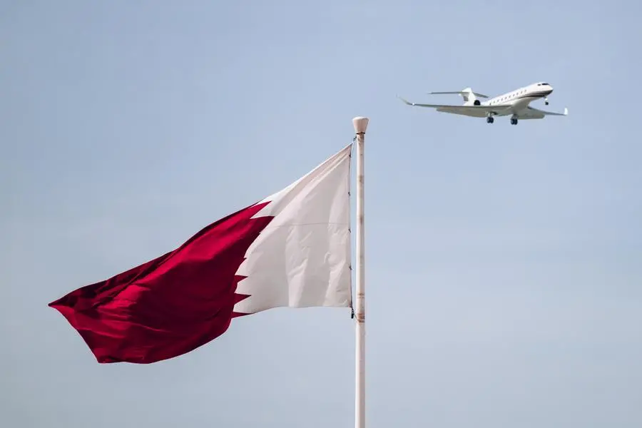 The waving flag of Qatar and an airplane flying nearby. Image used for illustrative purpose. Image courtesy: Getty Images/ Andrei Antipov , Getty Images