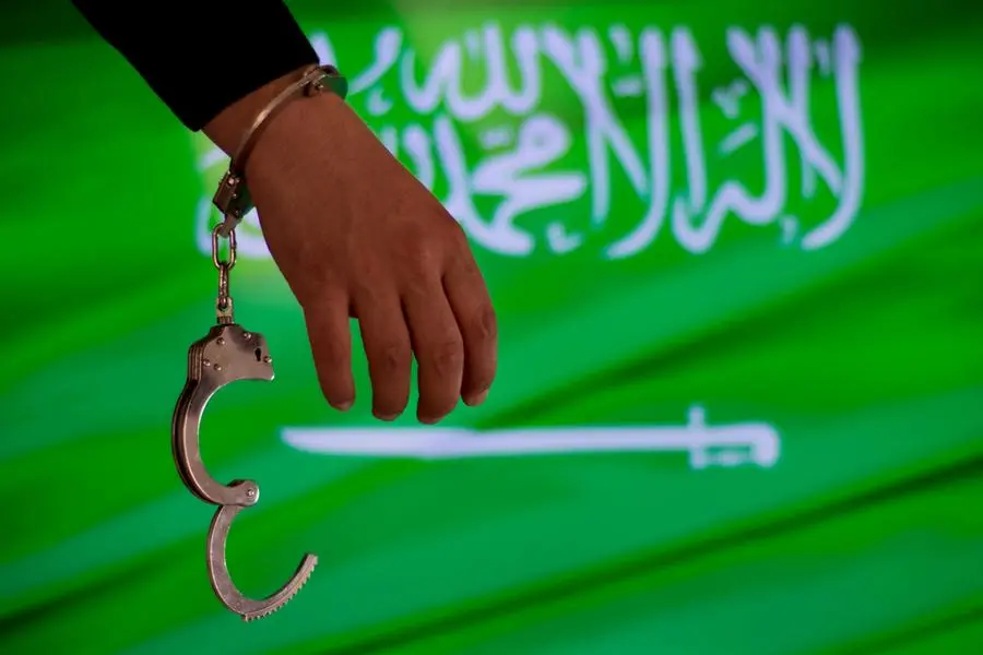 Handcuffs with hand in front of Saudi flag. Image Courtesy: Getty Images , Getty Images/iStockphoto