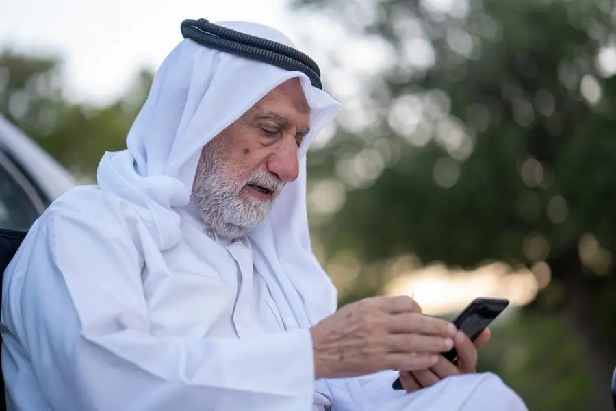 An old man wearing a white robe and a turban is sitting on the ground and looking at his cell phone. Image used for illustrative purpose. Getty Images , Getty Images