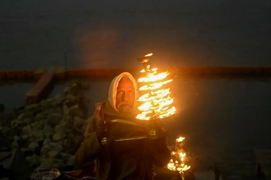 A priest performs evening rituals on the banks of Sarayu River, in Ayodhya on January 21, 2024, on the eve of the consecration ceremony of a temple to Hindu deity Ram. India's Prime Minister Narendra Modi will on January 22 inaugurate a temple that embodies the triumph of his muscular Hindu nationalist politics, in an unofficial start to his re-election campaign this year. (Photo by Money SHARMA / AFP)