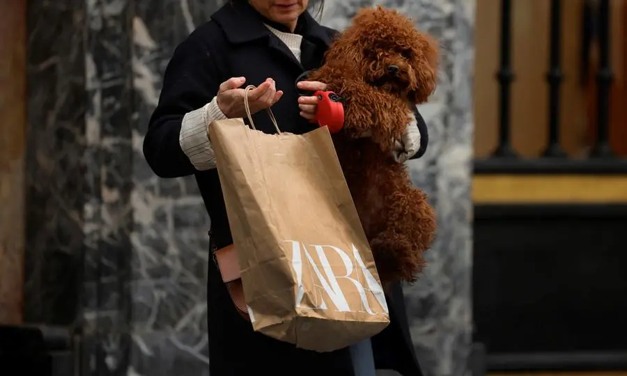 A woman carries a bag from Spanish multinational retail clothing chain Zara, while holding her dog, in the Gran Via of Bilbao, Spain, December 11, 2023. REUTERS/Vincent West