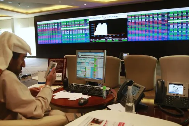 A trader uses his mobile phone behind his desk in front of the Qatar stock exchange board, in Doha February 4, 2014. REUTERS/Mohammed Dabbous , Reuters Images