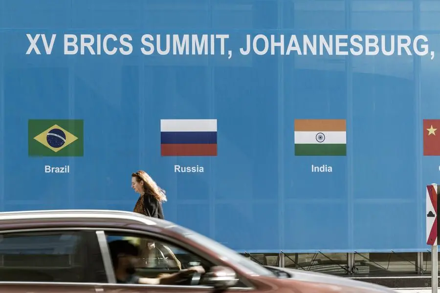 A woman walks past a poster for the 2023 BRICS Summit at the Sandton Convention Centre in Sandton, Johannesburg, on August 20, 2023. (Photo by MARCO LONGARI / AFP) Image used for illustrative purpose.