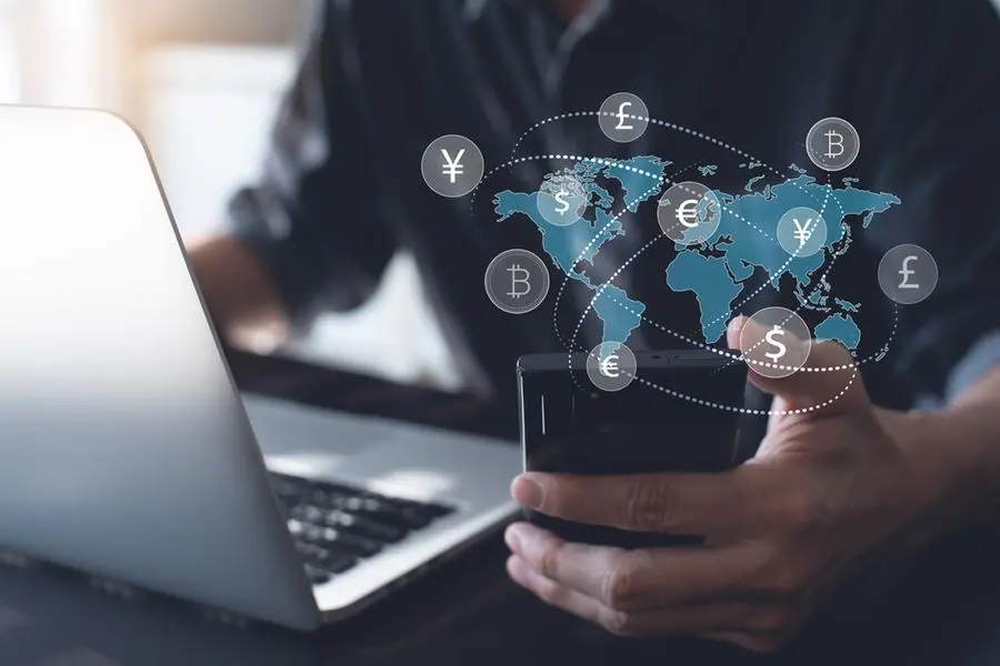 Currency exchange, money transfer, FinTech financial technology, Global business, online banking, interbank payment concept. Man using mobile phone and laptop computer with international currencies and world map on virtual screen. Image Courtesy: Getty Images , Getty Images/Getty Images/iStockphoto