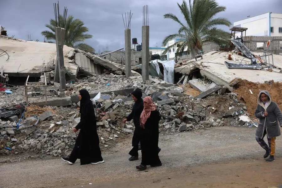 Palestinians walk past the destruction caused by Israeli strikes on their homes in the village of Khuzaa, east of Khan Yunis near the border fence between Israel and the southern Gaza Strip on November 27, 2023, amid a truce in battles between Israel and Hamas. The Israeli government said today it had put Hamas \\\"on notice\\\" that an \\\"option for an extension\\\" of the truce in the Gaza Strip was open. (Photo by SAID KHATIB / AFP)