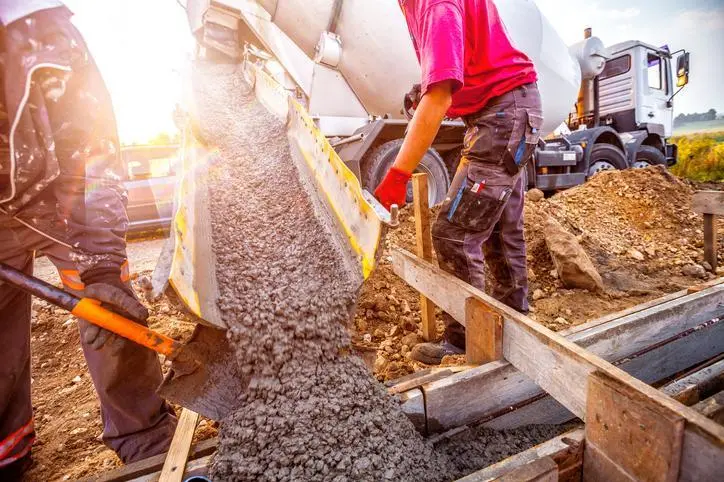 Pouring concrete to the foundations of the building. Construction Worker Guiding Cement Mixer Truck Trough. Cement Pouring from a Mixer Truck Chute. Concrete Foundation Construction. , Getty Images/Getty Images