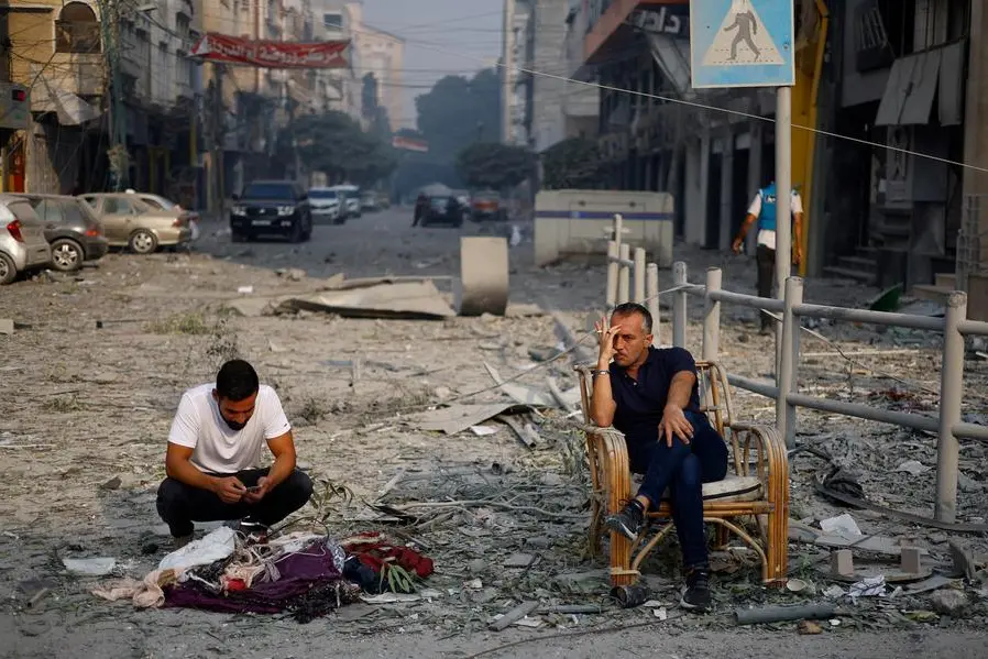 Palestinians sit on a debris-strewn street near the Watan Tower, which was destroyed in Israeli strikes, in Gaza City October 8, 2023. REUTERS/Mohammed Salem , Reuters