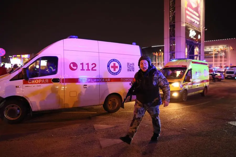 A law enforcement officer shouts outside the burning Crocus City Hall concert hall following the shooting incident in Krasnogorsk, outside Moscow, on March 22, 2024. Gunmen opened fire at a concert hall in a Moscow suburb on March 22, 2024 leaving dead and wounded before a major fire spread through the building, Moscow's mayor and Russian news agencies reported. (Photo by STRINGER / AFP)