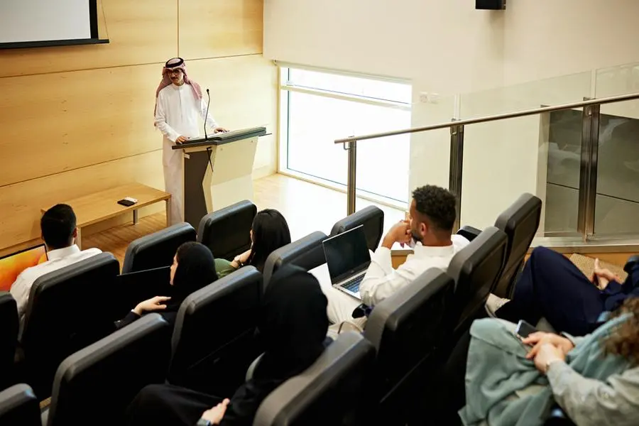 High angle view of Saudi professor speaking to students while standing on stage in auditorium. Image used for illustrative purpose. Getty Images , Getty Images