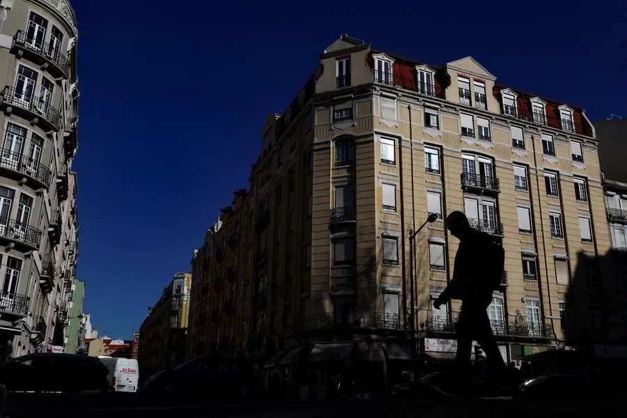 A person walks past buildings in Lisbon, Portugal, March 15, 2023. REUTERS/Pedro Nunes Image used for illustrative purpose. , Reuters