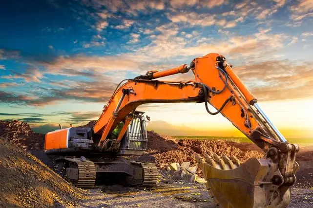 Excavator at a construction site against the setting sun. Excavator on the background of the setting sun. Huge excavator in the evening. Old excavator on a construction site. , Getty Images