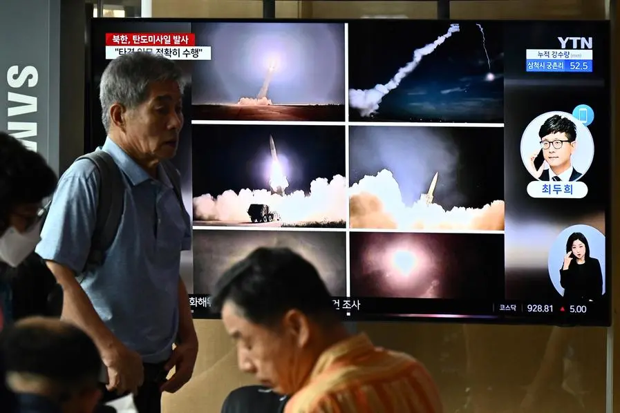 A man walks past a television showing a news broadcast with photos of a North Korean missile test, at a railway station in Seoul on August 31, 2023. (Photo by Anthony WALLACE / AFP)