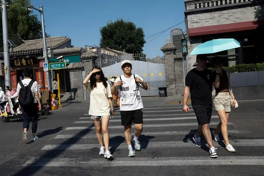 People walk across a street amid a yellow alert for heatwave, in Beijing, China June 21, 2023. REUTERS/Tingshu Wang , Reuters
