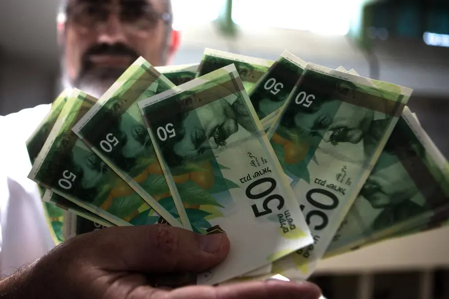 An employee of Bank of Israel holds new 50 Shekels\\' bills during a press conference at the bank\\'s headquarters in Jerusalem on September 10 2014. AFP PHOTO/MENAHEM KAHANA (Photo by Menahem KAHANA / AFP)
