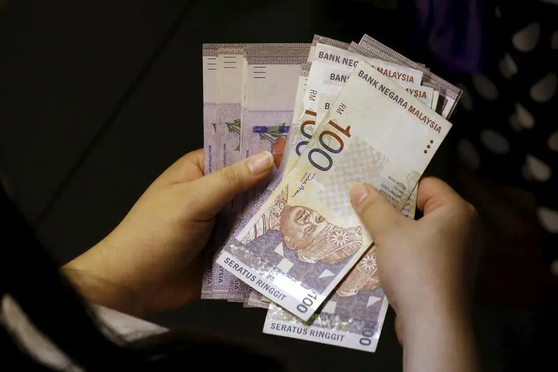 A customer counts her ringgit notes outside a money changer at the central business district in Singapore August 25, 2015. The Malaysian ringgit hit a fresh pre-peg 17-year low on Monday as sustained worries about China\\'s economy dented global risk appetite with European and Wall Street stocks suffering their largest one-day drop in nearly four years. REUTERS/Edgar Su - RTX1PJJ9 , Reuters Images