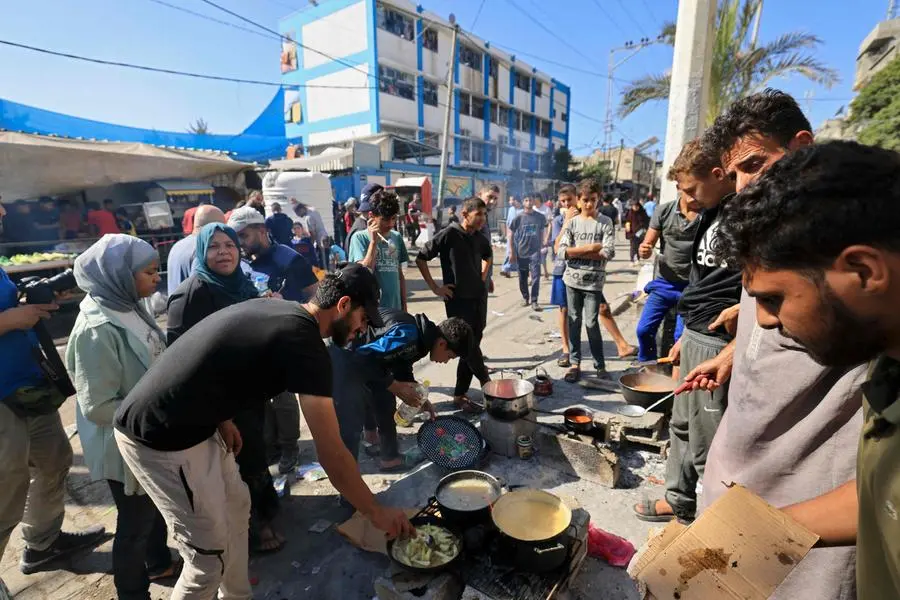 Displaced Palestinians prepare food in front of the United Nations Relief and Works Agency (UNWRA) school at the Nuseirat refugee camp in the central Gaza Strip on November 7, 2023, amid ongoing battles between Israel and the militant group Hamas. (Photo by Mahmud HAMS / AFP) , Agence France-Presse (AFP)/AFP