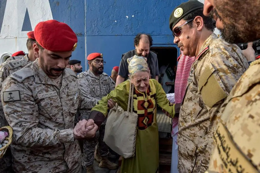 Saudi Navy sailors assist an elderly woman who has been evacuated from Sudan to disembark off a ferry passenger ship after arrival at King Faisal navy base in Jeddah on April 26, 2023 following a rescue operation amid a US-brokered ceasefire between the country\\'s warring generals. - A ship carrying 1,687 civilians from more than 50 countries fleeing violence in Sudan docked in Saudi Arabia on April 26, the foreign ministry said, the largest evacuation effort by the Gulf kingdom so far. (Photo by Amer HILABI / AFP) , Agence France-Presse (AFP)/AFP