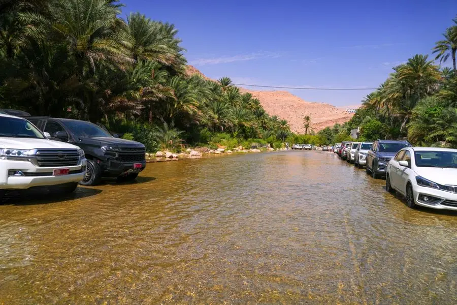 Flooded road, with parked cars, after the rain storm, along irrigation system on the way to refreshing swimming in oasis Wadi Bani Khalid. Getty Images Image used for illustrative purpose. , Getty Images