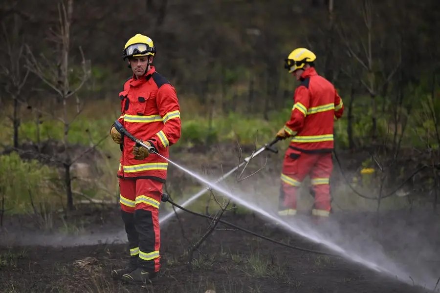 Firefighters from the Surrey Fire and Rescue Service use small pressure hoses used to extinguish small fires during a press preview at Hankley Common, the site of a wildfire during a heatwave in 2022, in Surrey, southeast England, on August 24, 2023. - At a military training site in Surrey, southeast England, a small team of firefighters blast the surrounding heathland with water as they practice tackling a different kind of enemy: climate change. The county\\'s fire service is investing in new equipment, training and tactics to respond to the threat of wildfires, which is growing as Britain\\'s climate becomes drier and more unpredictable. (Photo by Daniel LEAL / AFP)
