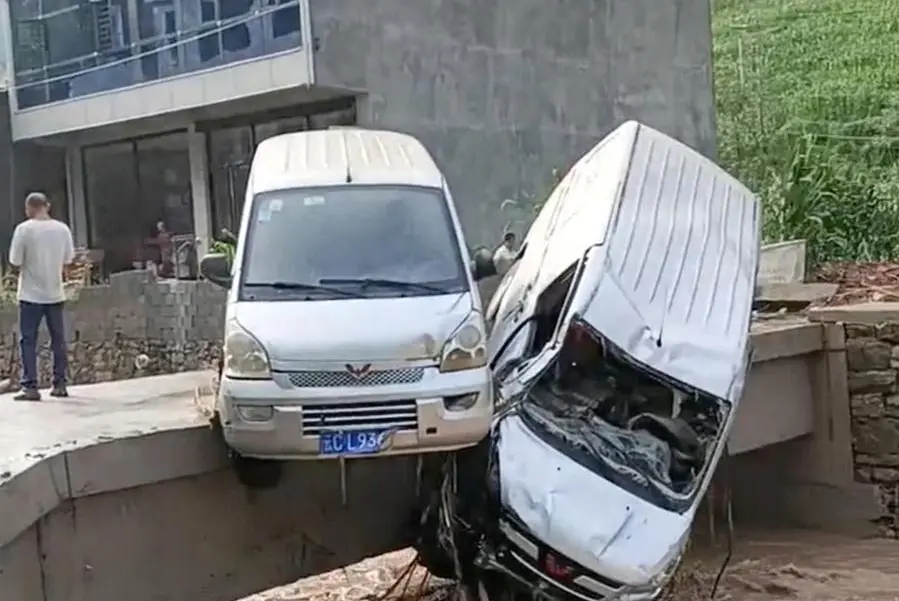 Vehicles hang over the edge of a bridge above flood waters following heavy rainfall in Zhenxiong County, Yunnan Province, China in this screengrab obtained from a handout video released on July 2, 2023. VIDEO OBTAINED BY REUTERS/Handout via REUTERS
