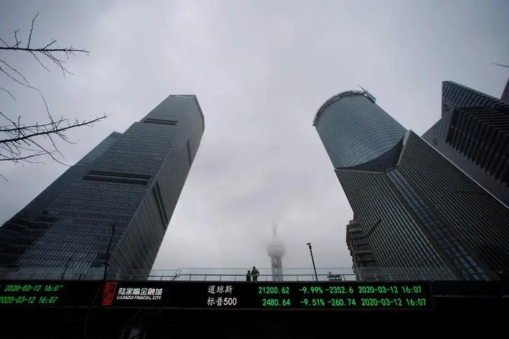 People are seen on a pedestrian overpass with an electronic board showing the Dow Jones and S&P 500 indexes, following an outbreak of the novel coronavirus in the country, at Lujiazui financial district in Shanghai, China March 13, 2020. REUTERS/Aly Song , Reuters Images/REUTERS