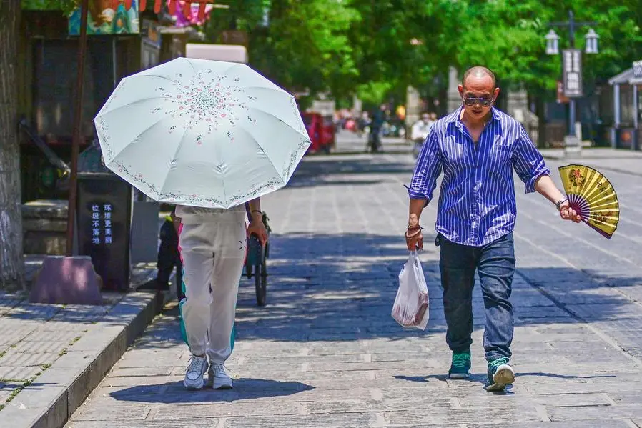 TOPSHOT - A resident uses an umbrella to shelter from the sun amid hot weather in Qingzhou, in China\\'s eastern Shandong province on June 15, 2023. (Photo by AFP) / China OUT , Agence France-Presse (AFP)/AFP