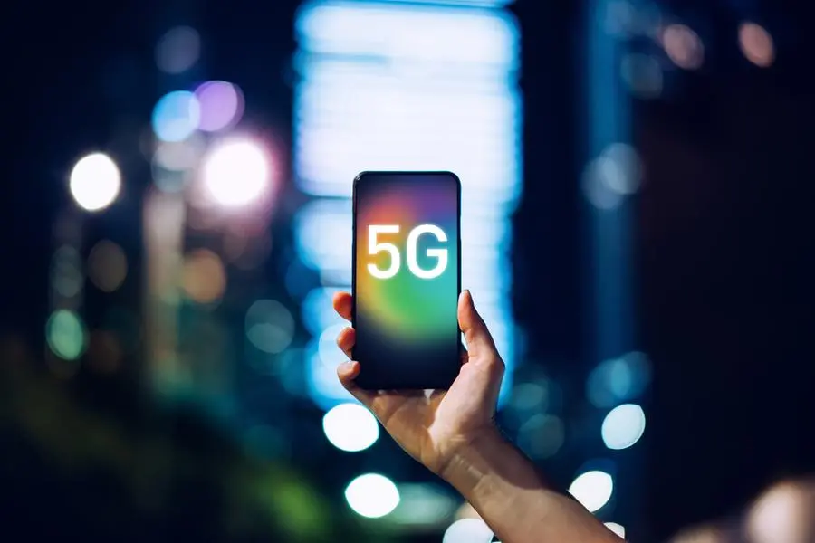 Close up of woman\\'s hand using smartphone against illuminated financial district in the city, with the concept of 5G communications technology. Image used for illustrative purpose. Image courtesy: Getty Images/ D3sign , Getty Images