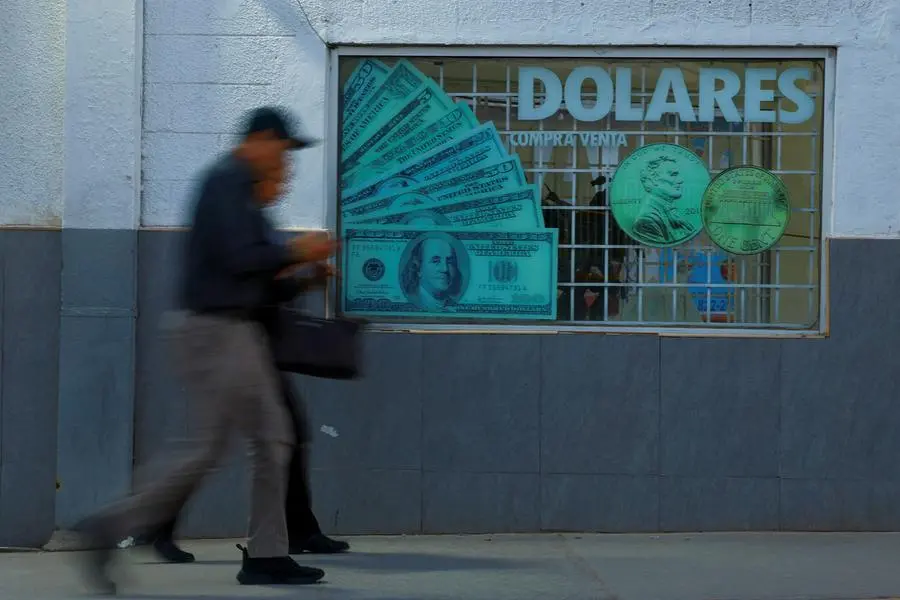 A man walks past dollars stickers on glass outside a foreign exchange house, after U.S. President Donald Trump said on Wednesday that he would temporarily lower new tariffs on many countries, in Ciudad Juarez, Mexico April 9, 2025.REUTERS/Jose Luis Gonzalez. , Reuters