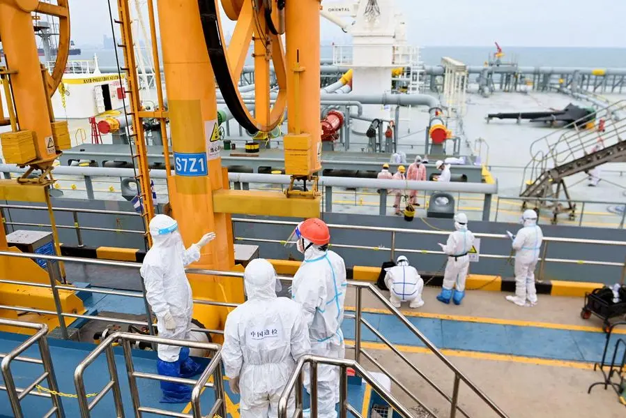 FILE PHOTO: Immigration inspection officers in protective suits check a tanker carrying imported crude oil at the port in Qingdao, Shandong province, China May 9, 2022. Picture taken May 9, 2022. China Daily via REUTERS.