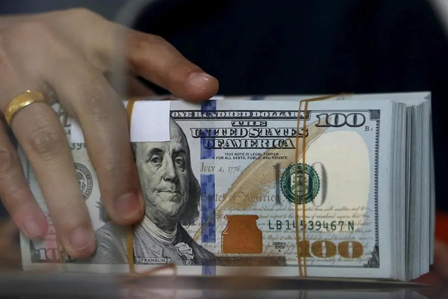 FILE PHOTO: An employee of a money changer holds a stack of U.S. Dollar notes before giving it to a customer in Jakarta, October 8, 2015. REUTERS/Beawiharta. , Reuters