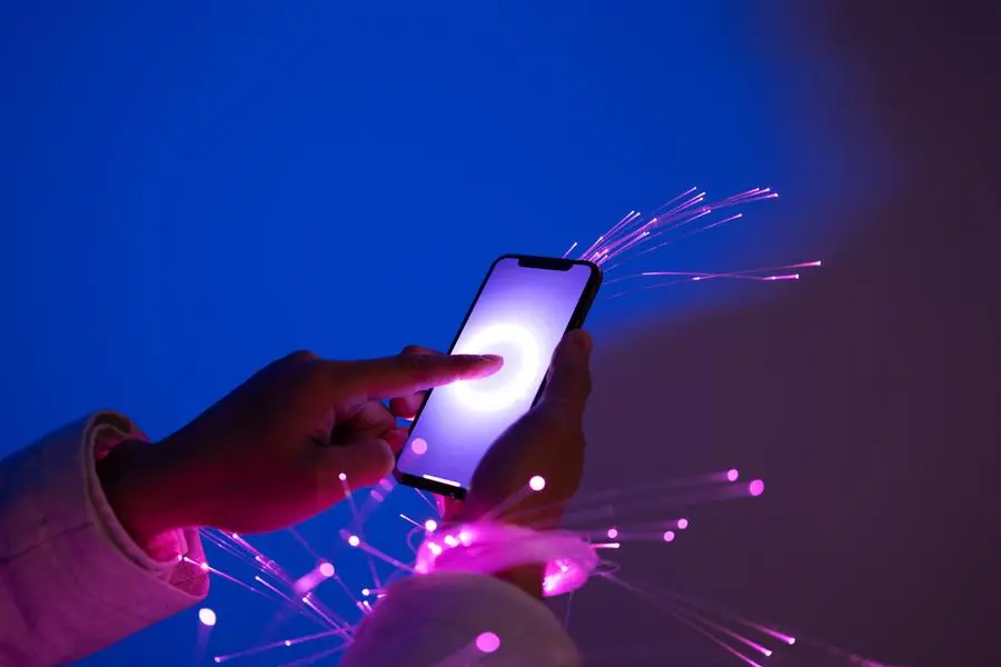 Close-up of holding smartphone, arms wrapped with fiber optics. Image used for illustrative purpose. Getty Images , Getty Images