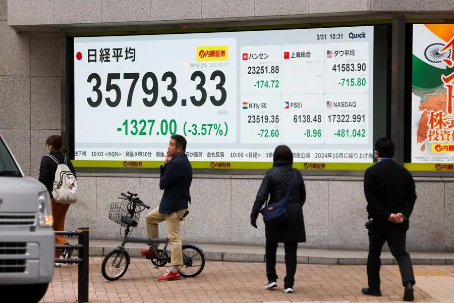 Pedestrians walk past a screen displaying Japan\\'s Nikkei share average outside a brokerage in Tokyo, Japan March 31, 2025. REUTERS/Manami Yamada. , Reuters