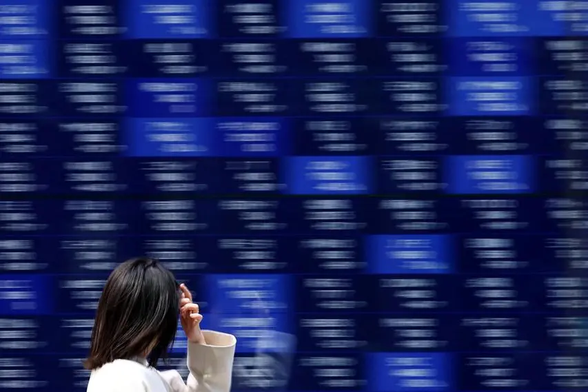 A woman walks past an electronic screen displaying stock quotation board in Tokyo, Japan April 15, 2025. REUTERS/Issei Kato. , Reuters