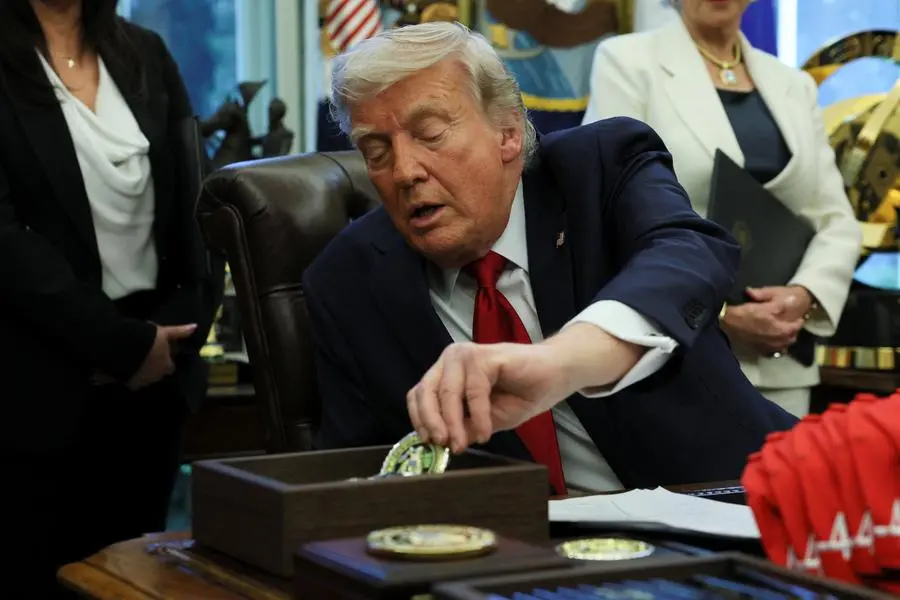 U.S. President Donald Trump picks up a challenge coin to hand to veterans during an executive orders signing event in the Oval Office at the White House in Washington, D.C., U.S., April 23, 2025. REUTERS/Leah Millis. , Reuters