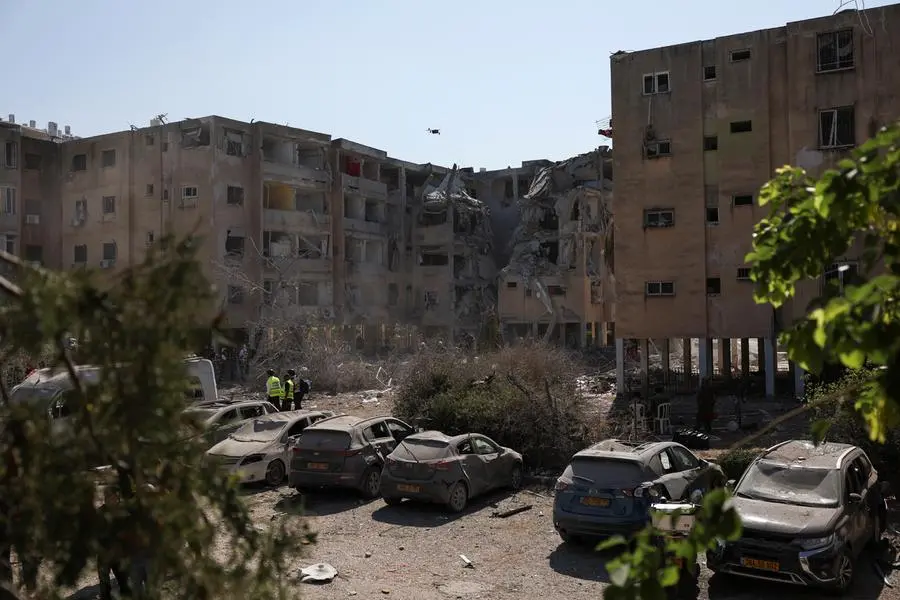 Emergency personnel walk near damaged vehicles at an impact site following a missile strike from Iran on Israel, in Holon, Tel Aviv, Israel June 19, 2025. REUTERS/Violeta Santos Moura , Reuters/REUTERS