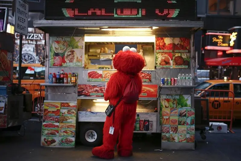 Jorge, an immigrant from Mexico, and dressed as the Sesame Street character Elmo, buys food from a street food cart in Times Square, New York July 30, 2014. Elmo and Cookie Monster have long delighted young viewers on TV\\'s \"Sesame Street,\" but the recent antics of New York street performers dressed as the beloved characters have drawn the ire of city officials and now the show\\'s producers. Sesame Workshop, which owns the rights to Big Bird, Ernie and the assorted puppet monsters on the 45-year-old program, said on July 29, 2014 it was drafting plans to stop performers who dress up as the characters from appearing in Times Square, where they pose for photos with tourists and then demand tips. Picture taken July 30, 2014. To match story USA-SESAME STREET/NEW YORK REUTERS/Eduardo Munoz (UNITED STATES - Tags: ENTERTAINMENT SOCIETY) - RTR40UDU , Reuters Images
