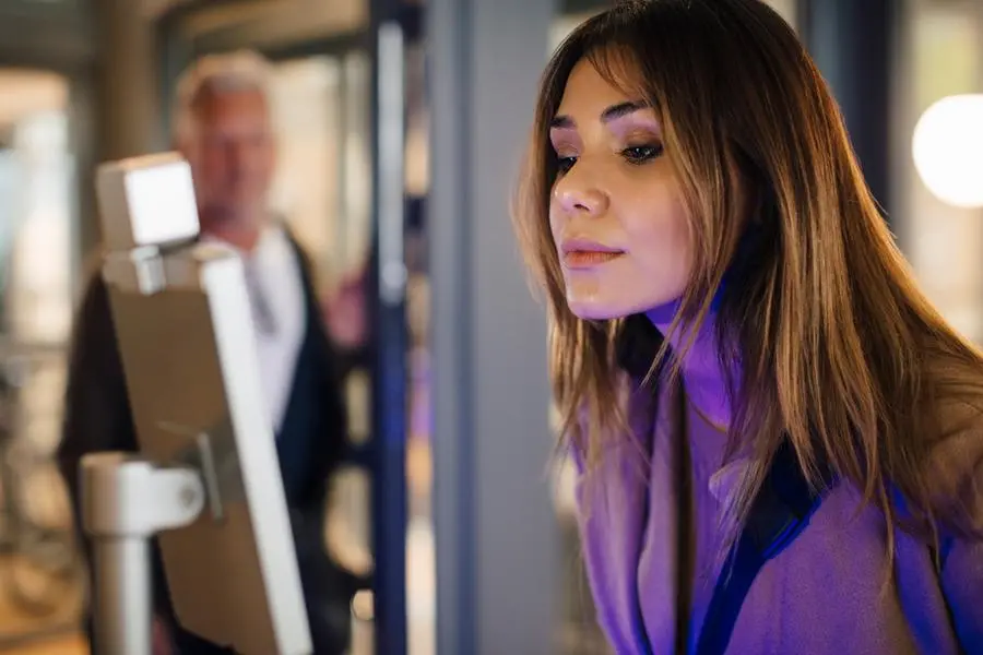 Female entrepreneur scanning face through recognizer while maintaining social distancing in office. Image used for illustrative purpose. Image courtesy: Getty Images/ Maskot , Getty Images